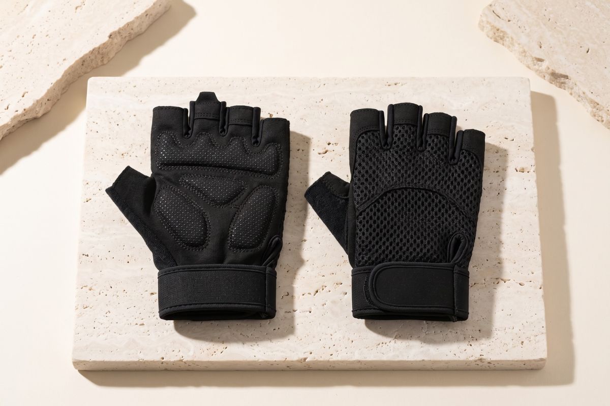 Black fingerless gym gloves displayed on pale stone platforms